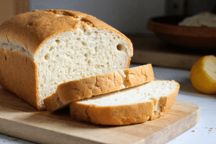 Golden crusted zero carb bread sliced on a wooden cutting board with airy texture and soft interior visible.