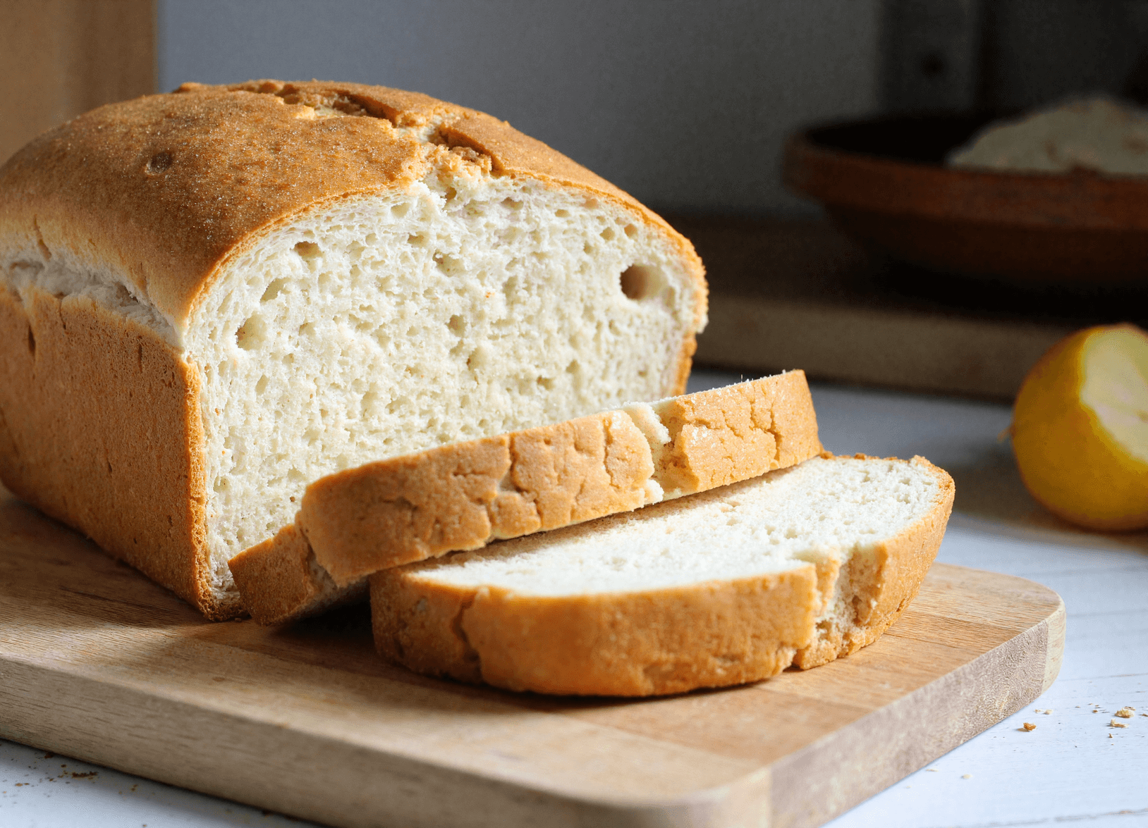 Golden crusted zero carb bread sliced on a wooden cutting board with airy texture and soft interior visible.