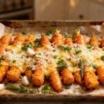 Golden smashed carrots roasted with Parmesan, garlic, and rosemary on parchment-lined baking tray.