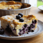 Slice of blueberry cottage cheese breakfast bake with powdered sugar and fresh blueberries on top.