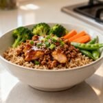 High-protein ground turkey teriyaki rice bowl with fresh vegetables and sesame seed garnish.