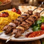 Grilled Persian koobideh beef kebabs with saffron rice, flatbread, fresh mint, and roasted tomatoes.