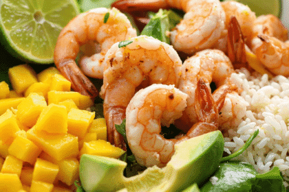 Fresh shrimp avocado mango bowl with rice, avocado slices, diced mango, and lime served over greens.