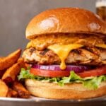 Grilled chipotle chicken burger with cheddar cheese, smoky chipotle sauce, lettuce, tomato, onion, and brioche bun served with sweet potato fries.
