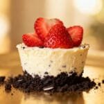 No-bake mini Oreo cheesecake cup topped with sliced strawberries and surrounded by Oreo crumbs.