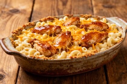 Cast iron skillet filled with creamy mac and cheese topped with honey garlic butter chicken and crispy breadcrumbs.