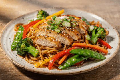 Chicken noodle stir fry with juicy sliced chicken breast, colorful vegetables, and glossy stir fry noodles on a plate.