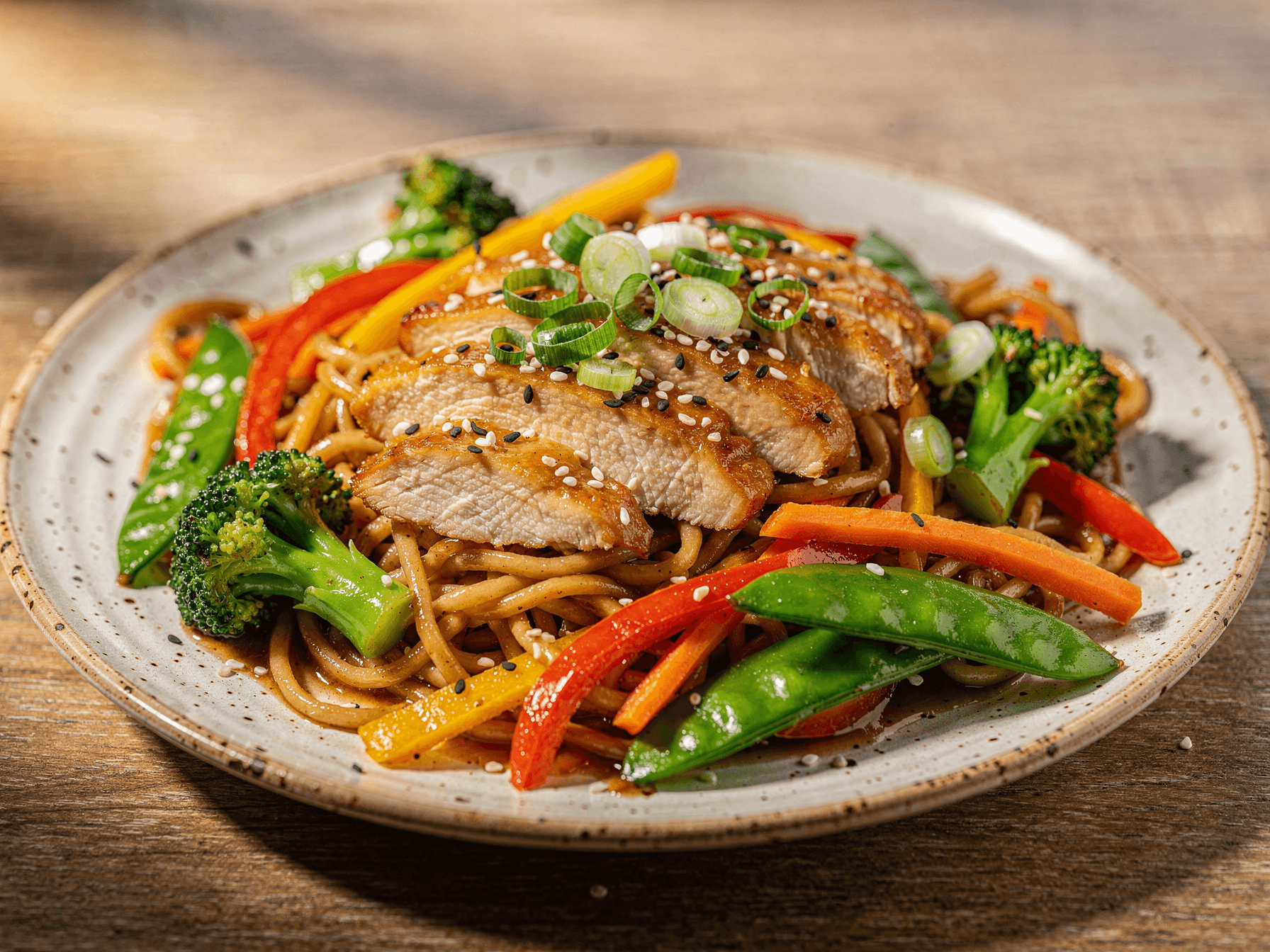 Chicken noodle stir fry with juicy sliced chicken breast, colorful vegetables, and glossy stir fry noodles on a plate.