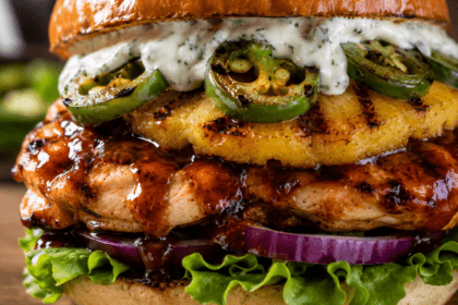 Extreme close-up of BBQ chicken pineapple burger showing grilled pineapple, jalapeños, creamy ranch sauce, and BBQ glazed chicken on brioche bun.