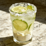 Close-up front view of Brazilian Lemonade with fresh lime slices, crushed ice, creamy lime drink texture, and chilled tropical beverage styling.