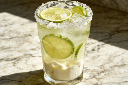 Close-up front view of Brazilian Lemonade with fresh lime slices, crushed ice, creamy lime drink texture, and chilled tropical beverage styling.