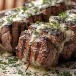 Close-up of juicy grilled steak kabobs topped with garlic herb butter, fresh parsley, and charred barbecue seasoning.