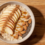 Top view of apple cinnamon oatmeal with sliced apples honey and almonds in a bowl