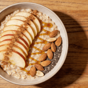 Top view of apple cinnamon oatmeal with sliced apples honey and almonds in a bowl