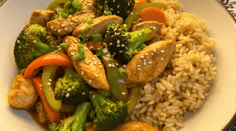 High-protein chicken stir fry with brown rice broccoli bell peppers and carrots in a bowl