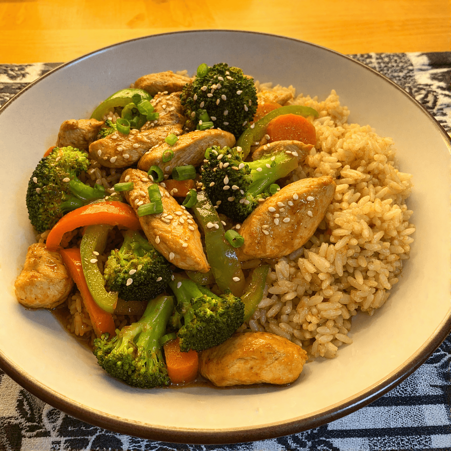 High-protein chicken stir fry with brown rice broccoli bell peppers and carrots in a bowl
