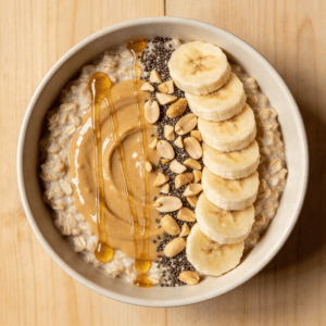 Top view of peanut butter overnight oats with banana, chia seeds, and oats in a glass jar on a clean background