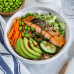 High-protein salmon rice bowl with crispy skin salmon avocado cucumber and vegetables