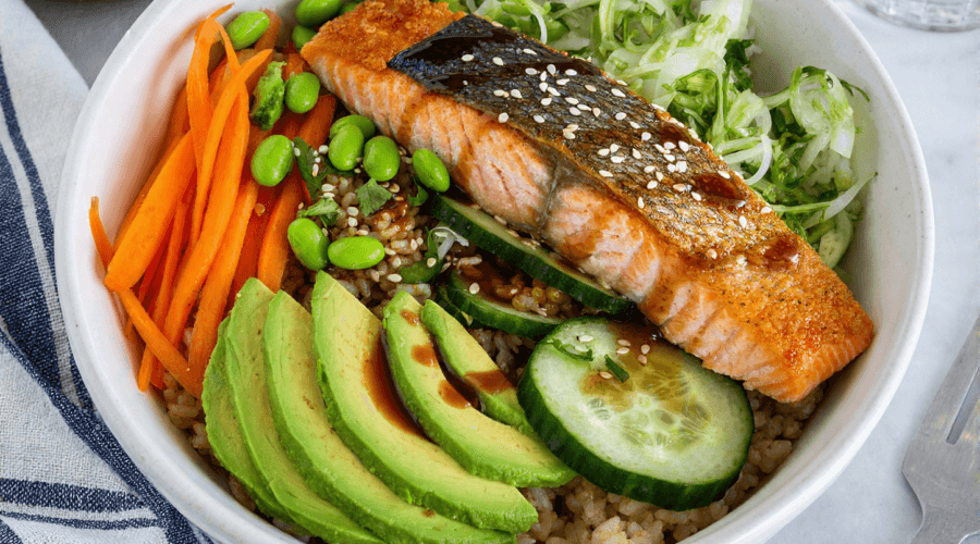 High-protein salmon rice bowl with crispy skin salmon avocado cucumber and vegetables