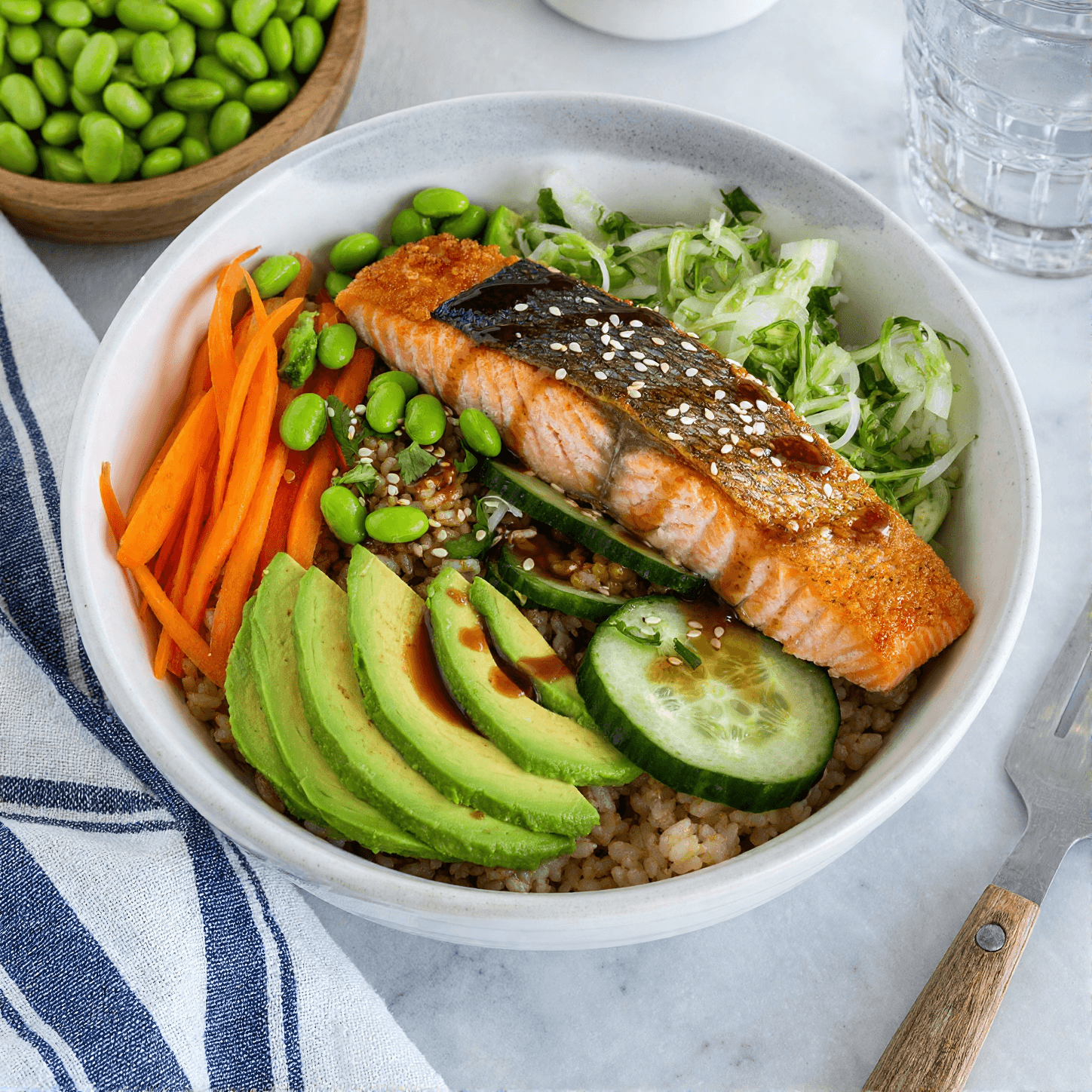High-protein salmon rice bowl with crispy skin salmon avocado cucumber and vegetables