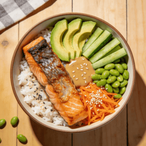 Top view of salmon rice bowl with avocado cucumber edamame carrots and sesame seeds