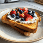High-protein yogurt toast topped with strawberries blueberries and honey on crispy golden bread