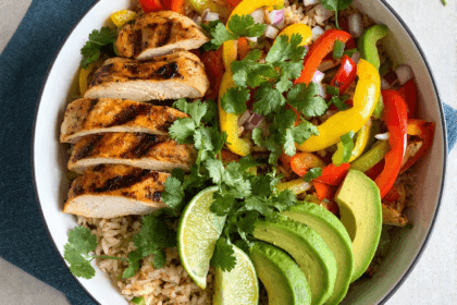 Top view of chicken fajita bowl with rice, grilled chicken, peppers, avocado, and lime