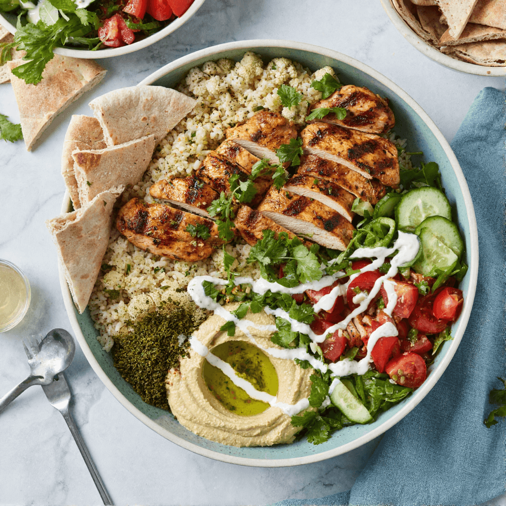 Top view of chicken shawarma bowl with grilled chicken, rice, vegetables, and pita