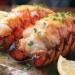 Close-up of grilled lobster tails brushed with garlic butter, fresh parsley, and lemon wedges.