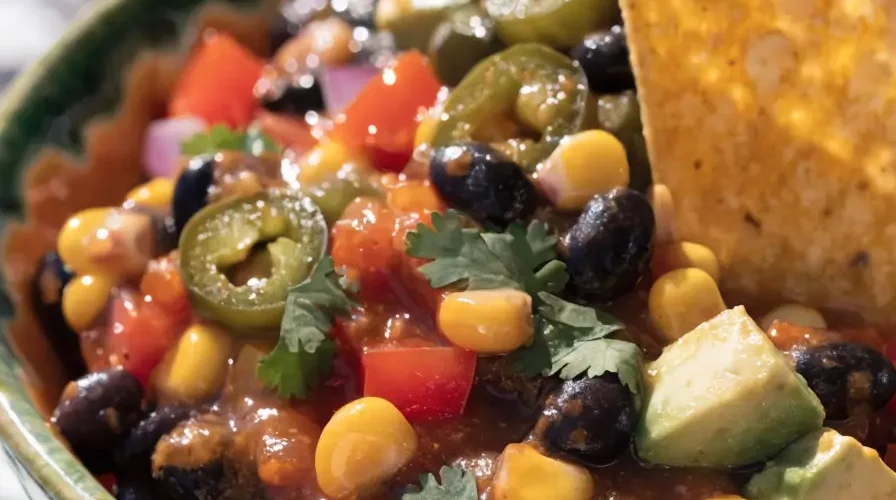 Close-up of loaded cowboy caviar dip with black beans, corn, avocado, tomatoes, peppers, and cilantro.